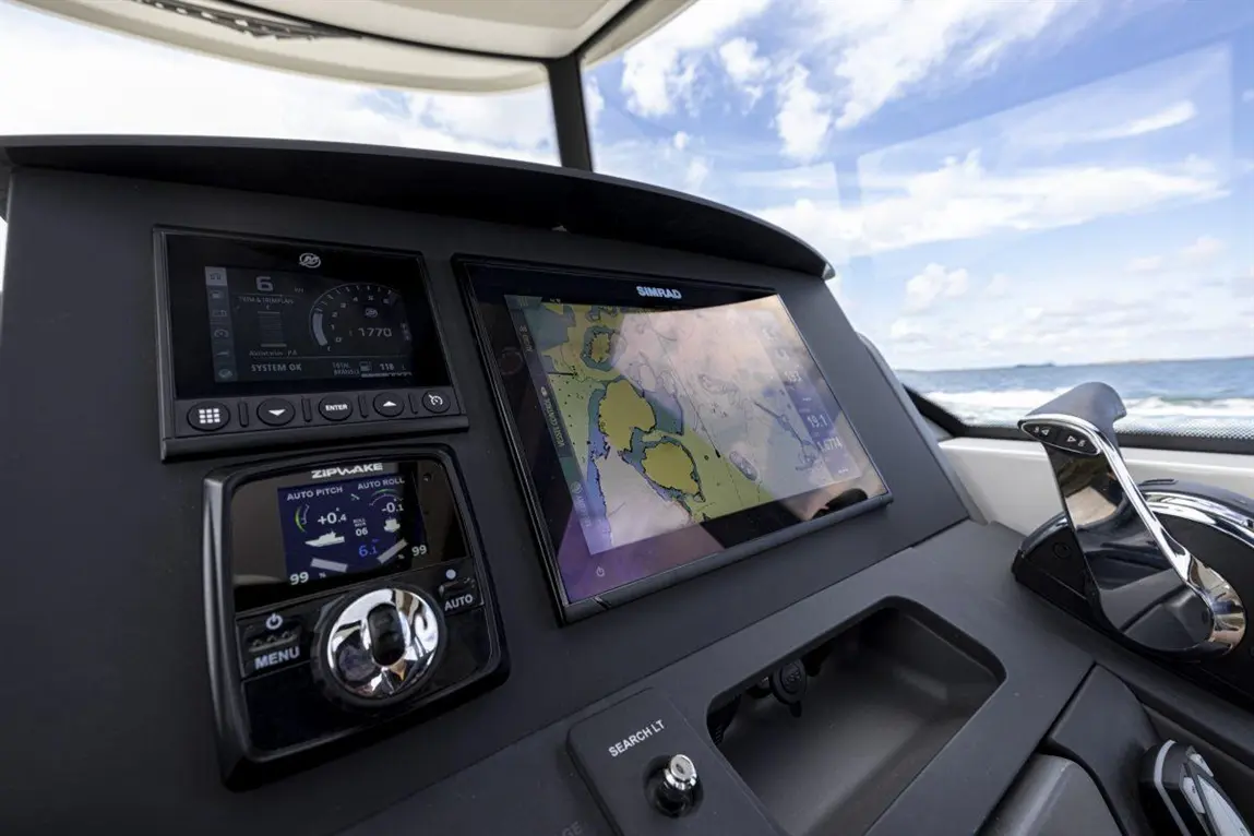 Boat dashboard featuring navigation screens displaying maps, controls, and instruments against a backdrop of open water and sky.